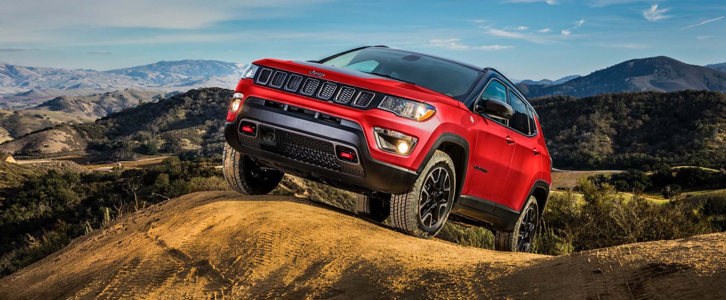 The 2021 Jeep Compass ascending a hill on a dirt track.
